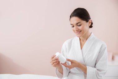 Beyaz vitamin şişesi tutan çekici bir kadın.