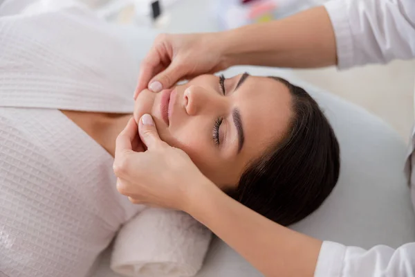 Masajista masajeando la barbilla en el salón de spa — Foto de Stock