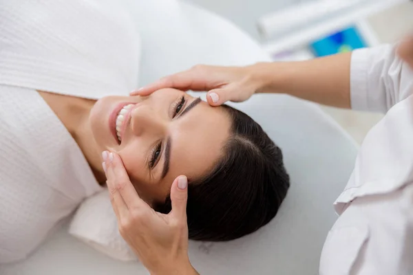 Joven alegre teniendo masaje facial en el salón de belleza — Foto de Stock