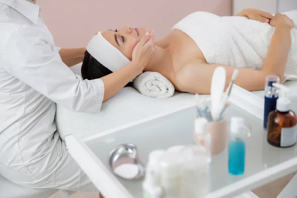 Masseuse massaging lady face at beauty salon — 스톡 사진