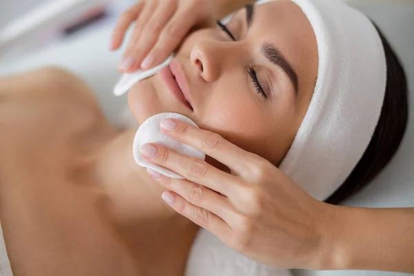 Beautician manos limpiando la cara de la señora con almohadillas de algodón —  Fotos de Stock