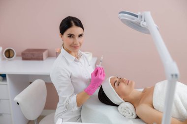 Gülümseyen güzellik uzmanı güzellik prosedürü için şırınga tutuyor.