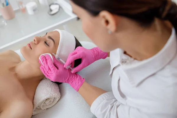 Doutor cosmetologista fazendo injeção no rosto da senhora — Fotografia de Stock