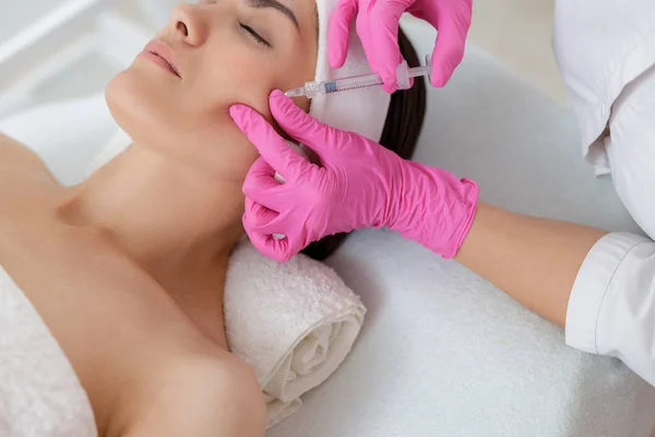 Beautician making injection in lady cheek at spa salon — 스톡 사진