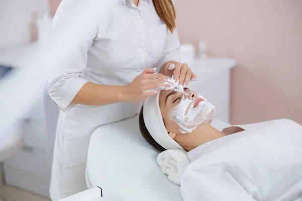 Cosmetólogo aplicando crema cosmética en la cara de la señora — Foto de Stock