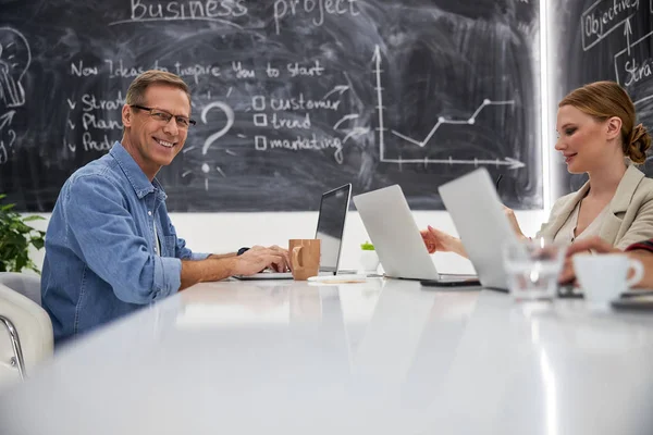 Hombre y mujer sonrientes trabajando en computadoras portátiles en la oficina — Foto de Stock