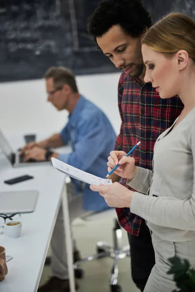 Charmante jonge vrouw tonen notities aan collega op het werk — Stockfoto