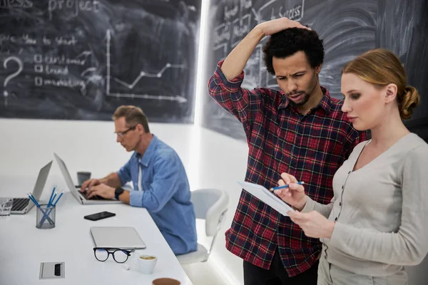 Mooie dame tonen notities aan verwarde collega op het werk — Stockfoto