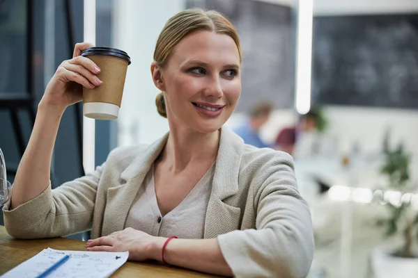 Радостная молодая женщина делает перерыв на кофе на работе — стоковое фото