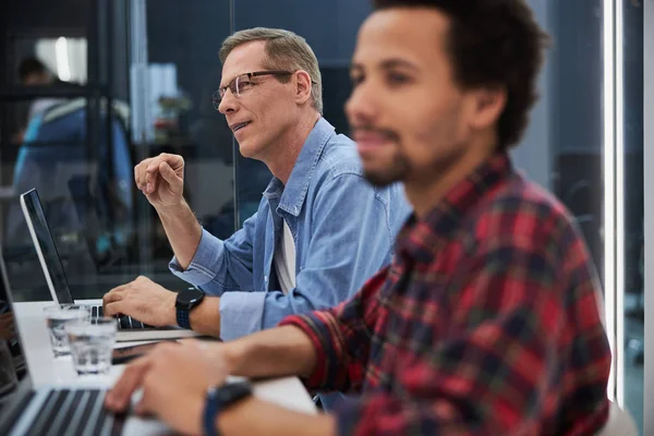 Hombre sonriente trabajando con un colega en una oficina moderna — Foto de Stock