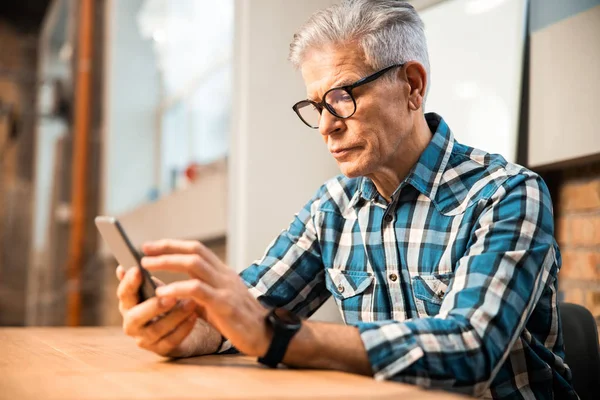 Homme adulte assis sur le lieu de travail avec smartphone — Photo