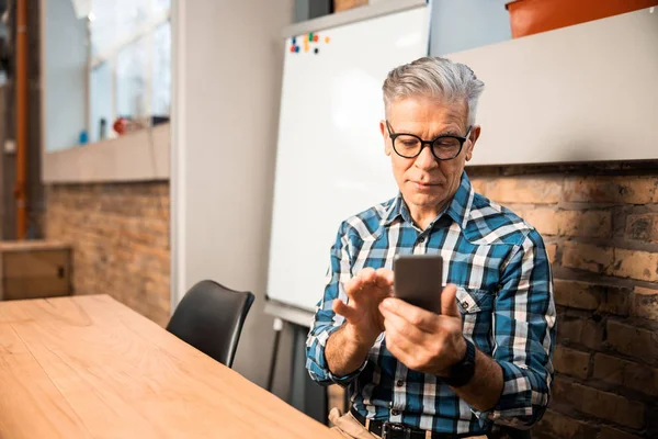 Mature man typing on mobile phone in the office — Stock Photo, Image