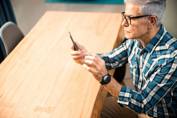 Mature man wearing glasses and sitting at the table — Stock Photo, Image