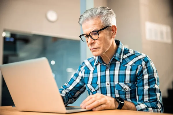 Дорослий чоловік сидить з ноутбуком на робочому місці — стокове фото