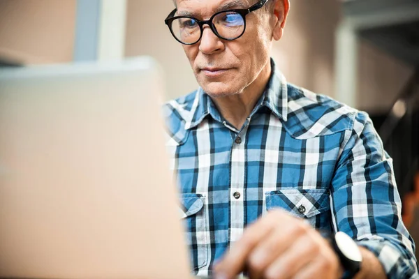 Usmívající se dospělý muž při pohledu na obrazovku notebooku v kanceláři — Stock fotografie