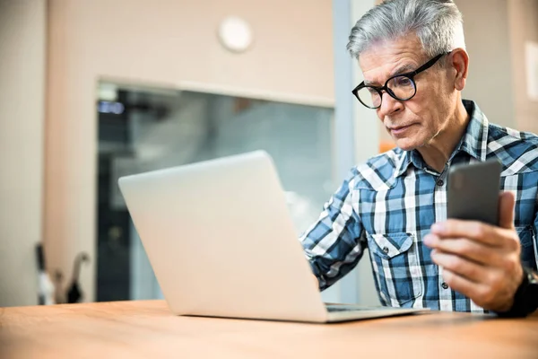 Akıllı telefonlu yetişkin bir adam laptopta çalışıyor. — Stok fotoğraf