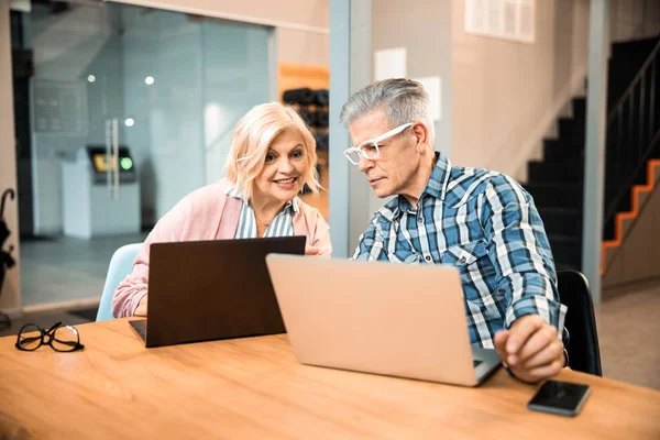 Glada vuxna par arbetar med bärbara datorer — Stockfoto