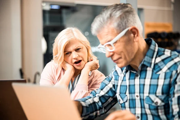 Förvånad kvinna sitter bredvid mannen på arbetsplatsen — Stockfoto