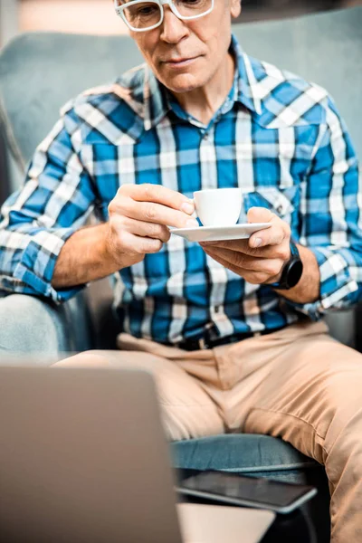 Gammal man i glas sittandes med varm dryck på caféet — Stockfoto