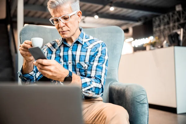 Adult male sitting in armchair while enjoying coffee — Stock Photo, Image