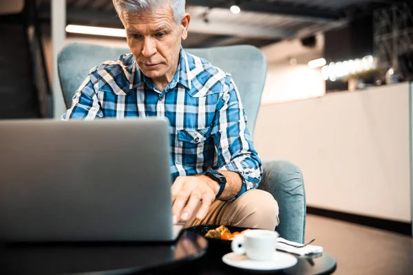 Mature man typing on laptop in cafe — Stock Photo, Image