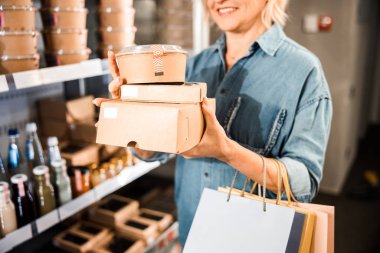 Alışveriş yaparken kutuları tutan mutlu yetişkin kadın.