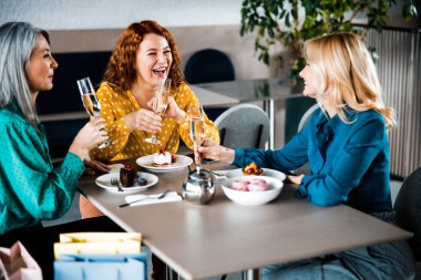 Neşeli bayanlar kafeteryada eğleniyor ve gülüyorlar.