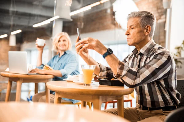Vuxen man håller smartphone på café — Stockfoto
