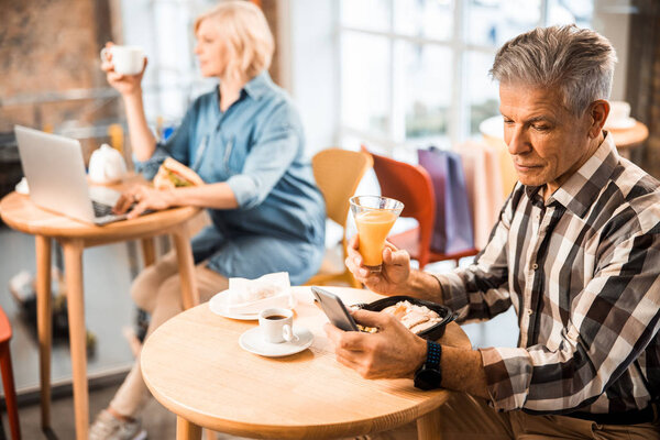 Smiling adult man enjoying juice in cafe