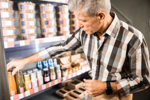 Homme adulte comparant des produits au supermarché — Photo