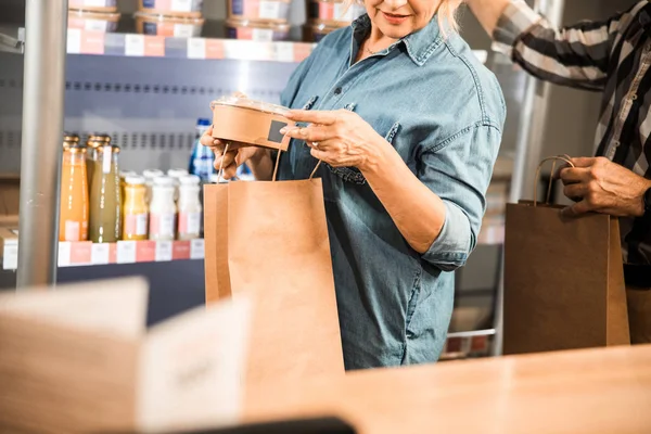 Erwachsene Frau hält Produkte im Laden — Stockfoto