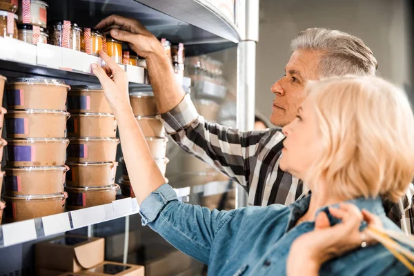 Adulte mari et femme debout près des étagères avec épicerie — Photo