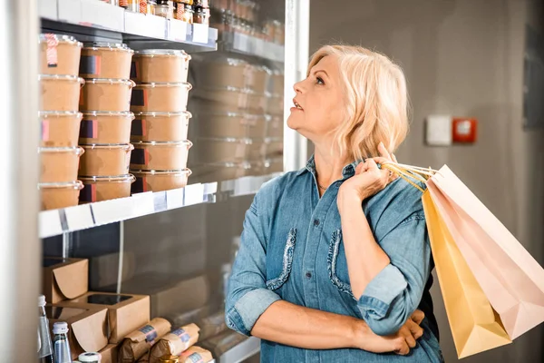 Belle femme adulte regardant sur des étagères avec des épiceries dans le magasin — Photo