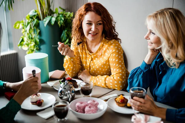 Fröhliche Frauen, die im Café Kuchen essen und Tee trinken — Stockfoto