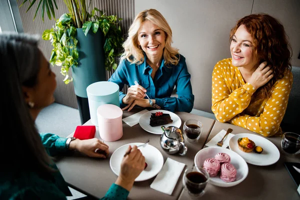 Fröhliche Frauen genießen Desserts und Getränke im Café — Stockfoto