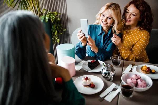 Charming ladies taking picture with smartphone in cafe — Stock Photo, Image