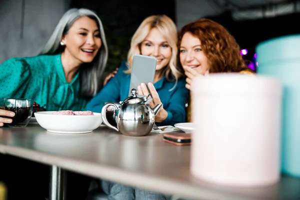 Fröhliche Damen, die auf dem Smartphone etwas Interessantes gucken — Stockfoto