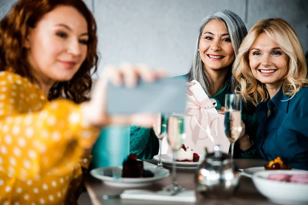Красивые улыбающиеся дамы делают селфи в кафе — стоковое фото