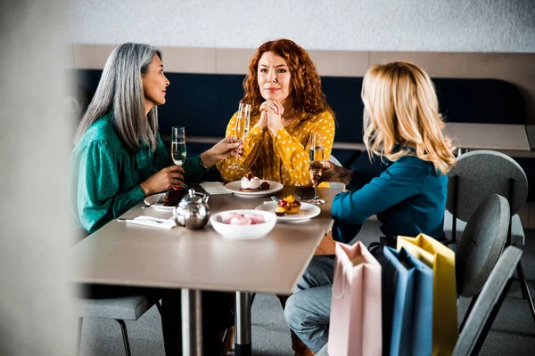 Encantadoras damas disfrutando de bebidas y charlando en la cafetería —  Fotos de Stock