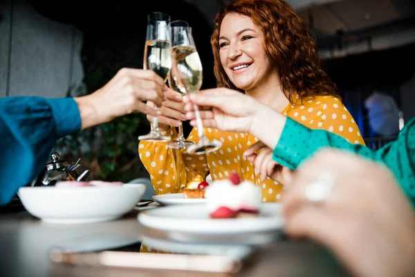 Веселая женщина, звенящая бокалами шампанского с друзьями — стоковое фото