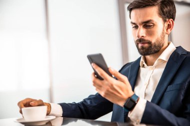 Modern ofis çalışanı cep telefonuna bakıyor.