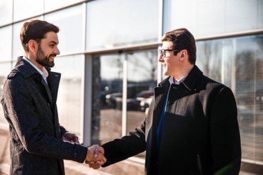 Gülümseyen iş ortakları dışarıda birbirlerini selamlıyorlar.