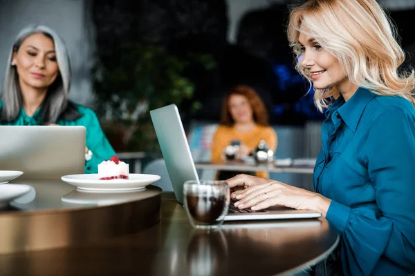 Leende kvinna som arbetar på modern anteckningsbok på café — Stockfoto