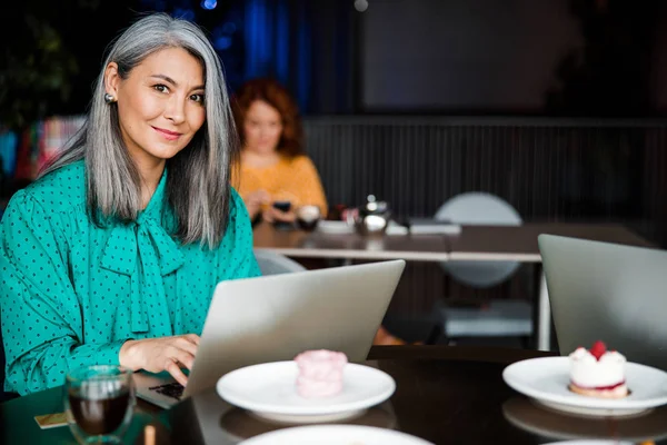 Schöne lächelnde Frau am Tisch mit Laptop — Stockfoto