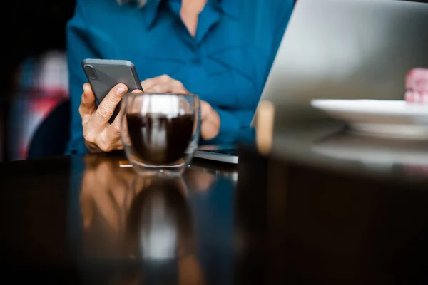 カフェで現代的なスマートフォンやノートパソコンを使う女性 — ストック写真