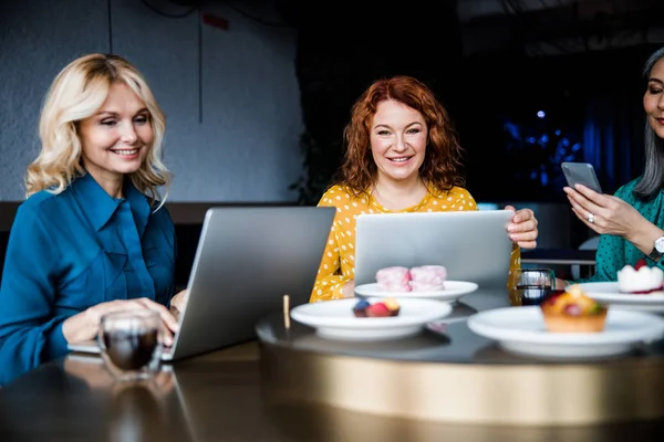 Cheerful ladies using modern technologies in cafe — Stock Photo, Image