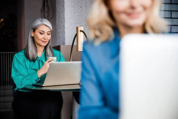 Hermosa mujer elegante usando el ordenador portátil en la cafetería — Foto de Stock