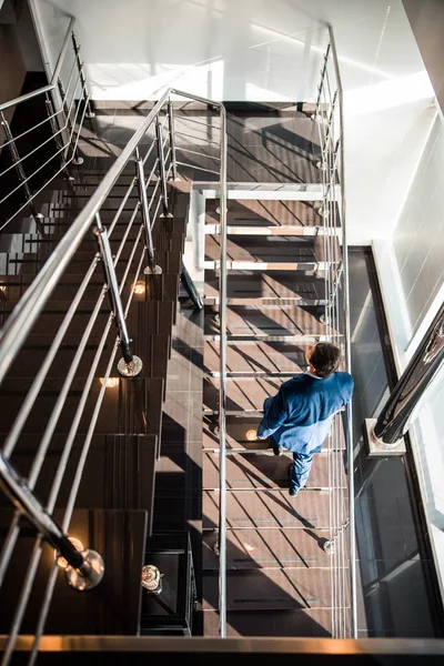 Modern middle-aged businessperson ascending the staircase alone — 스톡 사진