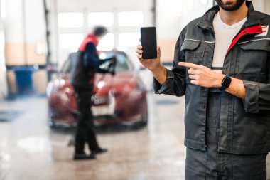 Kafkasyalı tamirci cep telefonunu işaret ediyor.