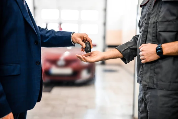 Trabalhador recebendo um carro chave fob de um homem de negócios — Fotografia de Stock